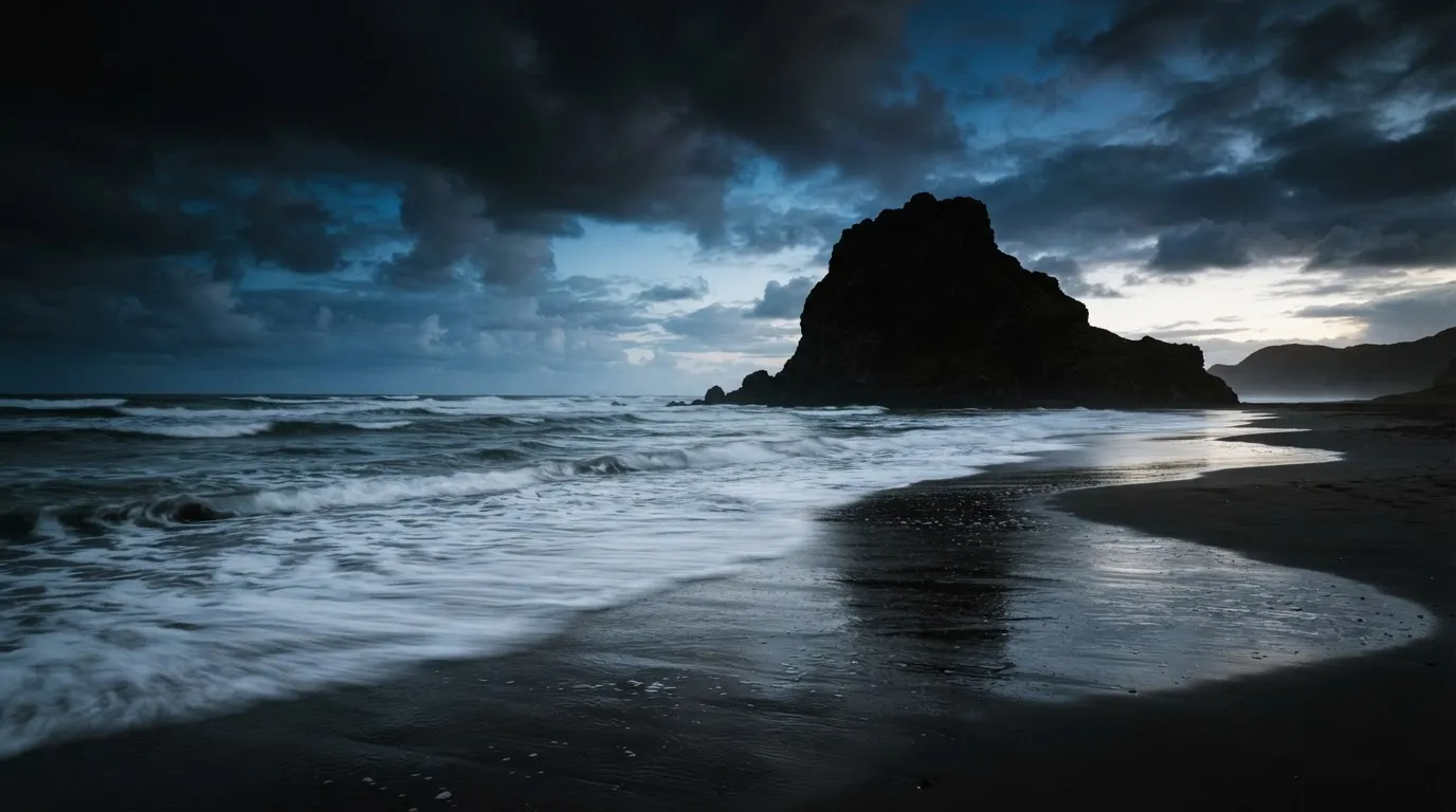 Wide cinematic shot of Piha beach on Auckland's West Coast at dawn with Lion Rock silhouette